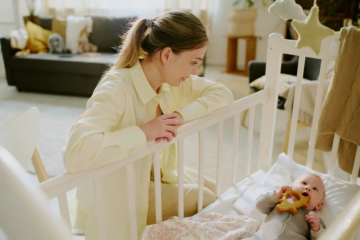 Une femme qui regarde son bébé dans son berceau avec son doudou