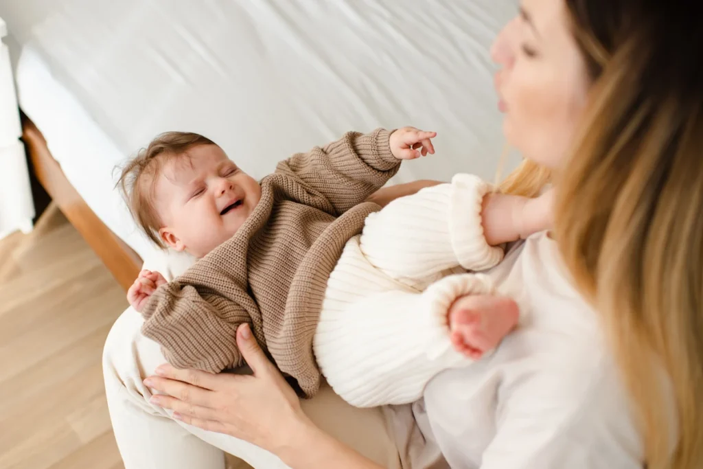 Un bébé ui pleure dans les bras de sa maman et qui refuse de dormir