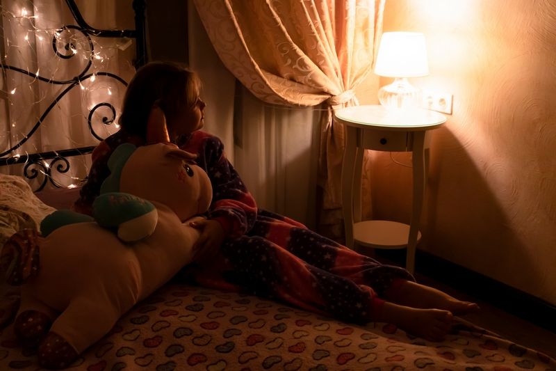 Petite fille assise sur son lit avec son doudou