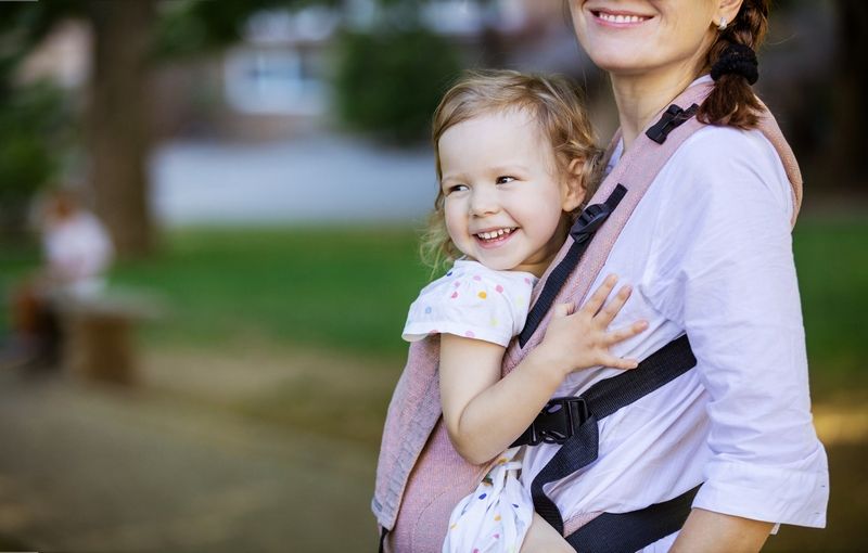 Maman portant son bébé dans un porte-bébé physiologique